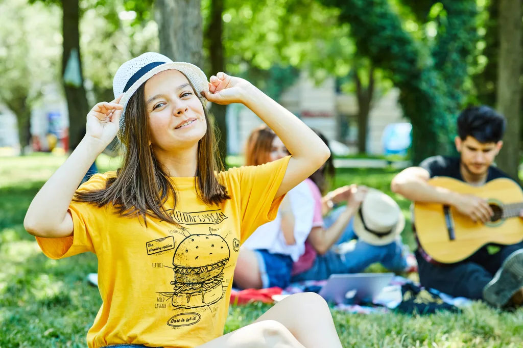 A young female with her friends having fun in park, sitting on the grass. High quality photo